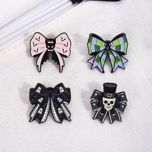Close-up of four gothic Halloween bow enamel pins with bat and ghost patterns