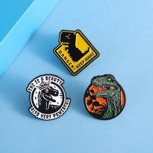 Three creative enamel dinosaur pins featuring warning signs and colorful illustrations