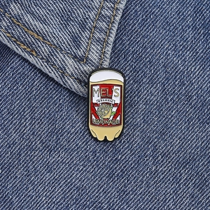 Close-up of a Lemonade soda can enamel pin on blue denim fabric with detailed metal texture
