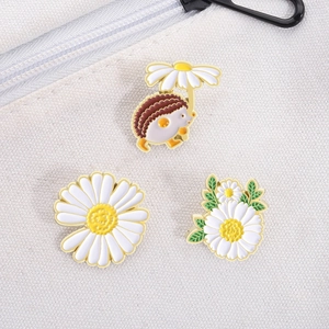 Detailed view of three cute enamel daisy and hedgehog pins on a white canvas bag