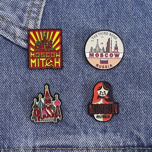 Detailed macro view of four Russian enamel pins with St. Basil's Cathedral and Matryoshka