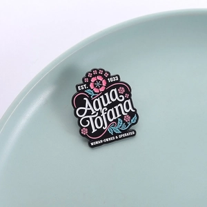 Detail of Aqua Tofana enamel pin with floral patterns on a ceramic tray display