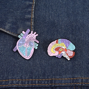 Detailed view of anatomical heart and brain enamel pins with medical terminology