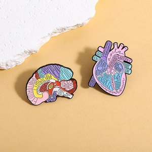 Anatomical heart and brain enamel pins with English medical labels on orange background