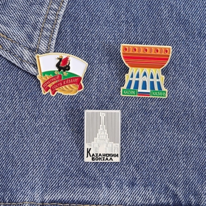 Vue détaillée de trois épinglettes émaillées des monuments de Kazan sur fond en denim bleu