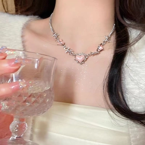 Close-up of pink heart pendant on silver thorn chain worn by a model in a Y2K style