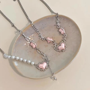 Pink heart necklace set with silver thorn chain and pearl splice details in a ceramic dish