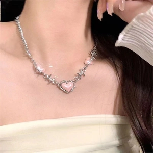 Close-up of pink heart thorn necklace with silver-tone chain on female model