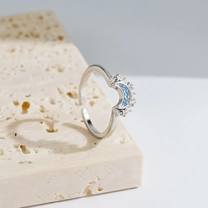 Bague croissant de lune en argent avec pierres bleues et diamants sur socle en pierre
