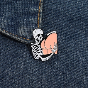 Detail of skeleton hugging pink heart enamel pin on blue denim jacket pocket
