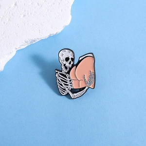 Macro detail of skeleton hands hugging buttocks enamel pin with gothic punk black metal finish