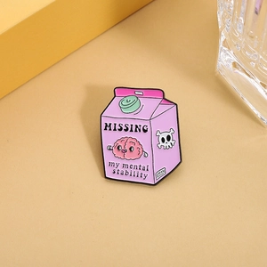 Detail of pink enamel pin showing 'MISSING my mental stability' text on milk carton