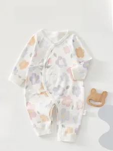 Detail of floral baby romper with side ties and wood bunny teether on soft background