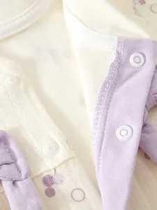 Detail of baby romper with eco-friendly resin snaps and purple cherry print pattern