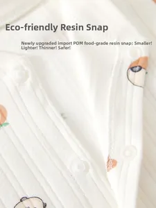 Detail of eco-friendly resin snap buttons on cotton baby romper with cartoon pattern