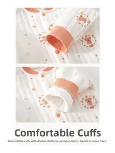 Close-up of quilted baby bodysuit cuff with cartoon bear prints and orange piping trim