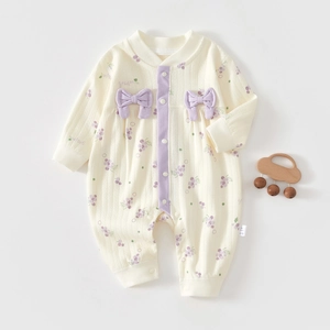 Detail of baby romper with grape patterns, purple bows, and soft cotton fabric texture