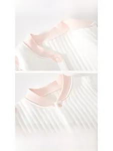 Détail de l'encolure en cœur du barboteuse bébé avec bord rose et boutons-pression