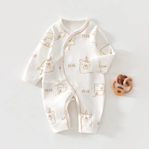 Flat lay of white cotton baby romper with cute brown bear print and side tie closure