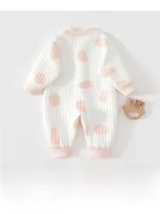 Détail d'une grenouillère thermique avec pois roses et poignets côtelés doux sur tissu blanc