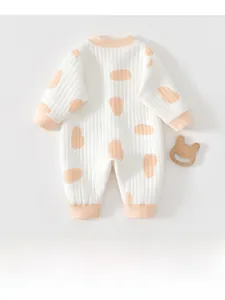 Detail view of cotton quilted baby romper with orange pebble print and ribbed cuffs