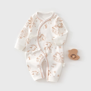 Detailed flat lay of white cotton baby romper with cartoon toy prints and side ties