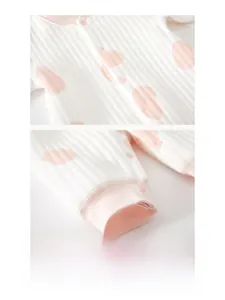 Détails des boutons-pression et poignets roses côtelés sur la grenouillère bébé