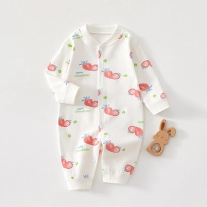 Close-up of baby white cotton romper with strawberry print and wooden rattle detail