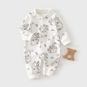 Detail of white cotton baby romper with koala print and wooden bear teething toy