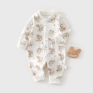 Detail of floral baby romper with snap buttons and a wooden bear teething toy