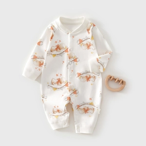 Detailed flat lay of white long sleeve baby romper with cartoon bird print and wooden teether