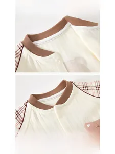 Détail d'un body bébé en coton avec texture côtelée, écusson ours et poignets à carreaux