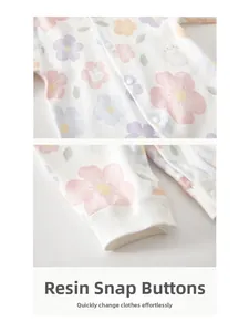 Detail of resin snap buttons on long sleeve cotton baby romper with floral print