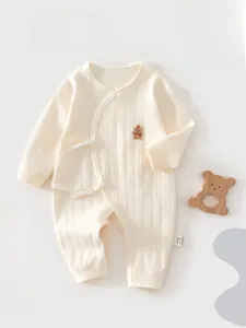 Close-up of cream knit baby romper with ribbed texture and bear embroidery detail