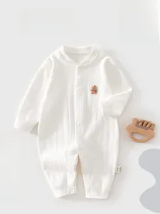 Detail eines weißen gerippten Baby-Stramplers aus Bio-Baumwolle mit Bären-Stickerei