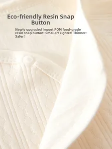 Detail of eco-friendly resin snaps on soft cotton newborn bodysuit with ribbed texture