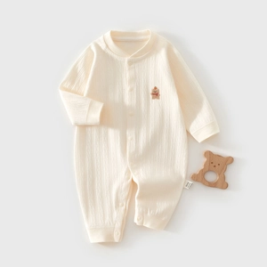 Detail eines cremeweißen Baby-Einteilers aus Rippbaumwolle mit kleiner Bärenstickerei