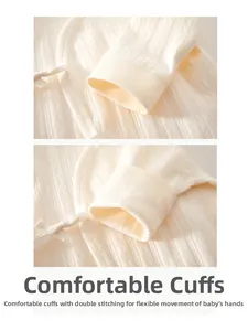Detail of warm white cotton baby bodysuit showing textured fabric and cuffed sleeves