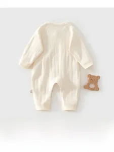 Detailed view of cream baby knitted romper with vertical diamond texture and wooden bear toy