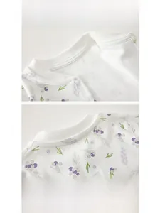Detail of baby onesie neckline featuring purple berry print and shoulder snap buttons
