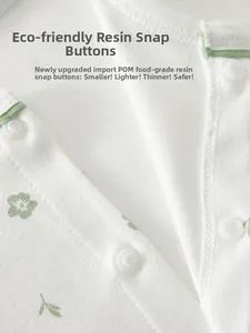 Macro detail of white cotton baby romper featuring floral print and resin snap buttons