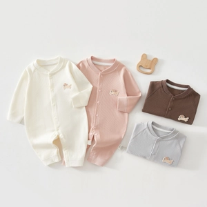 Détail des barboteuses en coton côtelé pour bébé avec broderie chiot et étiquette de soin