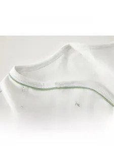 Detail of newborn cotton kimono top showing soft hemmed neckline and leaf patterns