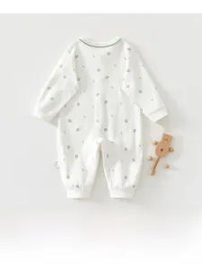 Flat lay of baby long sleeve cotton romper with floral print and wooden bear rattle accessory