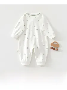 Detail of floral infant bodysuit with smooth cotton texture and decorative wooden rattle