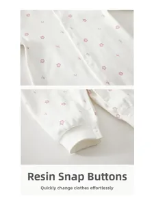 Detail of baby cotton romper with pink floral print and white resin snap buttons