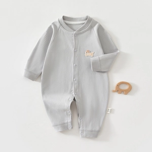 Détail d'un barboteuse bébé à manches longues avec maille côtelée et broderie de chiot