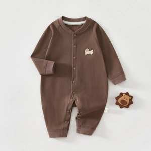 Détail de grenouillère en coton côtelé avec broderie chien et jouet lion en bois