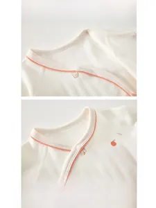Detail of baby cotton romper neckline with soft orange piping and secure snap buttons