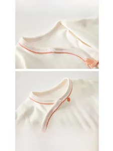 Detail of baby bodysuit bound neckline with orange contrast trim and soft ribbed cotton fabric